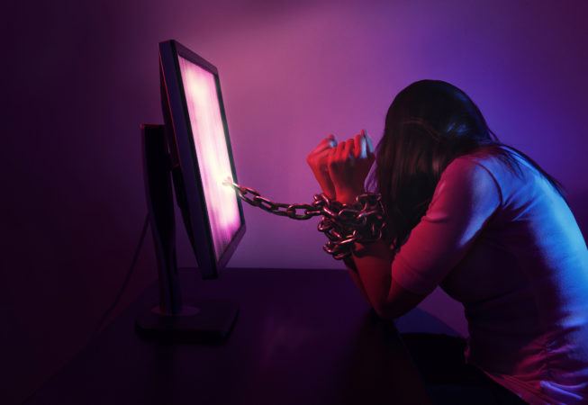 A woman is chained to a computer at night.