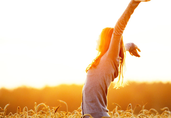 Young woman enjoying nature and sunlight in straw field